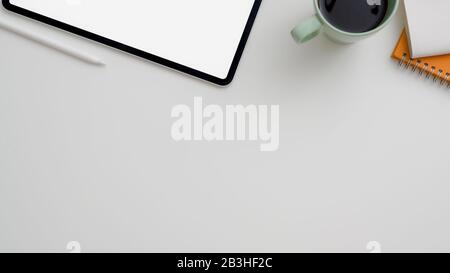 Top view of minimal workplace with bank screen tablet, coffee cup, notebooks and copy space on white table Stock Photo