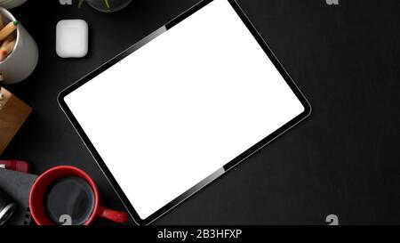 Top view of stylish workplace with mock-up tablet, stylus and red coffee cup on black table Stock Photo