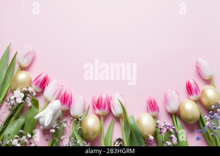 Easter frame of pink tulips, golden egg and bunny on pastel pink. Top view with copy space. Happy Easter holiday. Greeting card. Stock Photo