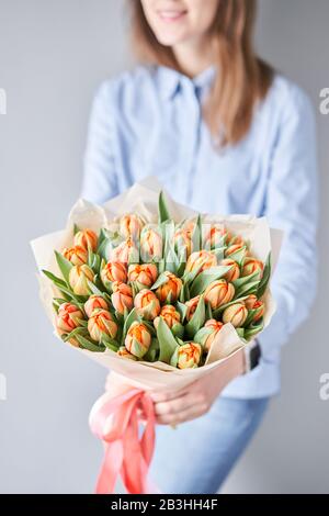 Bunch of fresh cut spring flowers in female hands. Orange color tulips in woman hand. Young beautiful woman holding a spring bouquet. Stock Photo