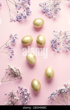 Easter composition of golden egg purple flowers on pastel pink. Top view with copy space. Happy Easter holiday. Greeting card. Stock Photo