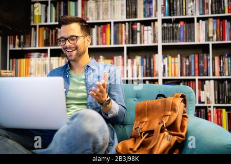 Happy student working on laptop in library Stock Photo