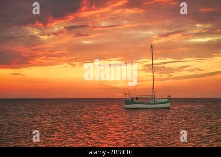 Sailboat in the sea against sunset sky Stock Photo