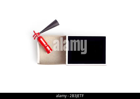 Tiny fire extinguisher inside an opened black match box, top view on white Stock Photo