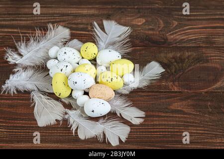 Easter, colored eggs on a light background, holiday background for your decoration. Near willow branches, feathers. Copy space Stock Photo