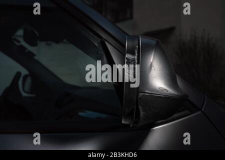 The heavily scratched rear view mirror of a silver car. Stock Photo