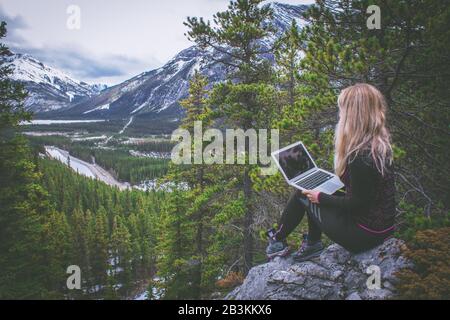 Digital nomad woman working on her laptop in the mountains Stock Photo