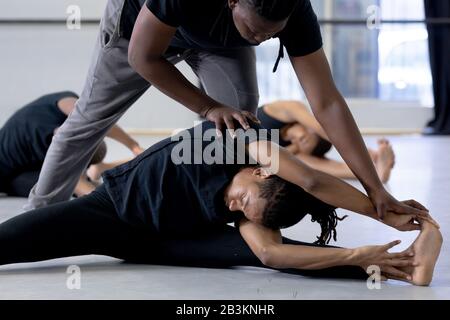 Male dancer helping modern dancers stretching up in a studio Stock Photo