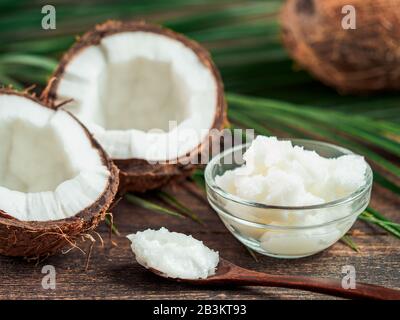 Liquid coconut MCT oil and halved coco-nut on wooden table. Health Benefits of MCT Oil. MCT or medium-chain triglycerides, form of saturated fatty acid. Stock Photo