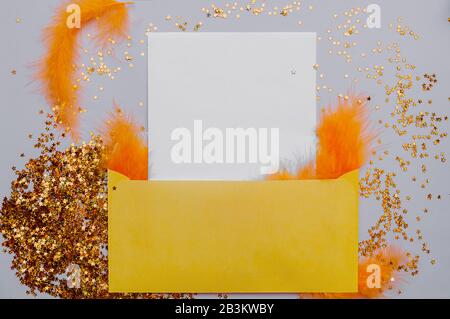 Yellow covert with a white blank sheet with Golden stars and orange feathers with space for text on a smooth pink background. Ready-made layout for th Stock Photo