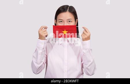 Asian woman wearing hygienic face mask painting Vietnam flag to protect from the Coronavirus 2019 (COVID-19) infection outbreak situation, the virus o Stock Photo