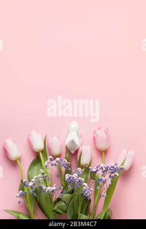 Easter bouquet of pink tulips, and bunny on pink background. Top view with copy space. Happy Easter holiday. Vertical greeting card. Stock Photo
