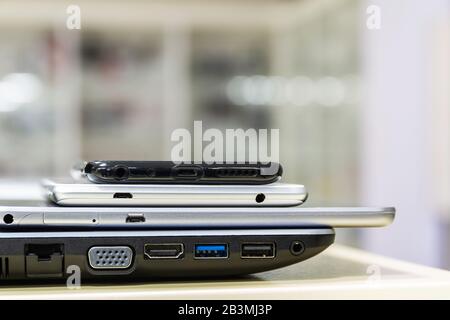 Modern computer gadgets are on the store shelf. Smartphones and tablet are on the laptop. Side view, closeup, selective focus Stock Photo