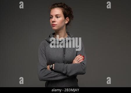 Sport caucasian female in grey hoodie, picture isolated on grey background Stock Photo