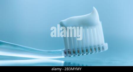Transparent plastic toothbrush with white toothpaste. Macro image. Stock Photo