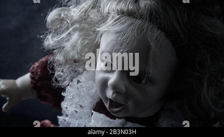 Old colourless ugly doll with a frill dress and open mouth Stock Photo