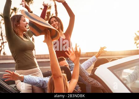 Happy friends having fun on convertible car in road trip - Group young people enjoying vacation together in tropical city Stock Photo