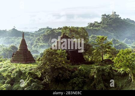 The view from Shin Mra War Pagoda, showing small stupas on small jungle covered hills with mountain ridges in the background, Mrauk U, Rakhine, Myanma Stock Photo