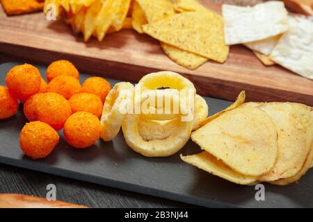 Mix of snacks : pretzels , crackers , chips and nachos on the table Stock Photo