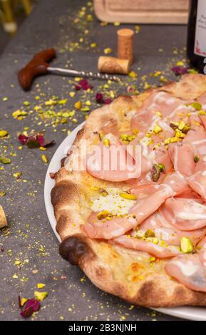 Rustic mortadella topped pizza with red wine at Italian restaurant Stock Photo