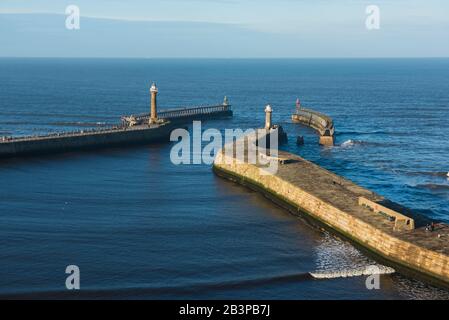 Aerial view of small coastal harbour entrance with defence walls and lighthouse Stock Photo