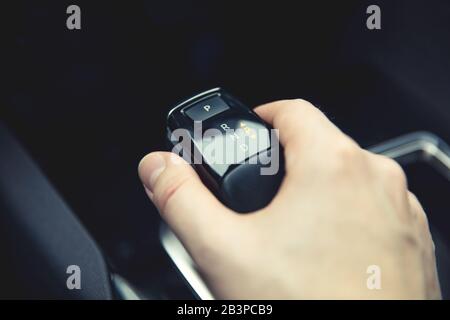 Man holds stick of automatic gearbox in modern car. Stock Photo
