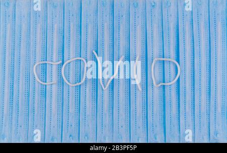 the word COVID on background of surgical protective masks. Medical respiratory bandage face.  Stock Photo