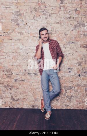 handsome smiling mans talking on mobile phone on the brick wall background Stock Photo