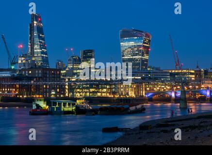 City of London buildings at night, viewed from the South Bank, with the Millennium Bridge and the Walkie Talkie Tower Stock Photo