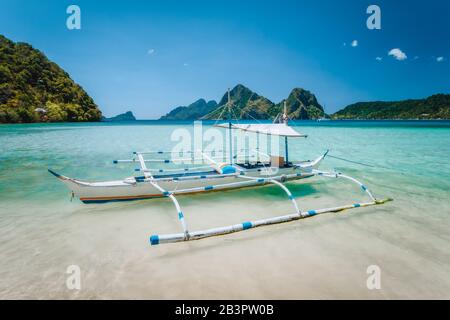El Nido, Palawan, Philippines. Local tourist banca boat for island hopping trip. Beautiful mountains in background Stock Photo
