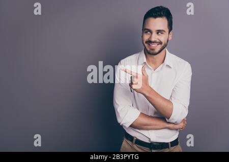 Photo of handsome business man friendly smiling indicating finger empty space advising novelty product interesting offer wear white office shirt pants Stock Photo