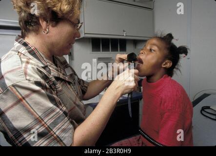 Austin Texas USA (undated): Doctor examines throat of young Black school student. The doctor's clinic travels to schools serving low-income students and offers free medical checkups. ©Bob Daemmrich Stock Photo