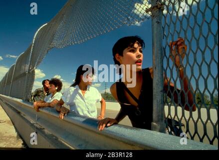 Juarez Mexico: Mexican teen looks through break in fence on Mexican side of channelized Rio Grande River on the border between Mexico and the United States. The Texas city of El Paso is on the other sde of the river. ©Bob Daemmrich Stock Photo