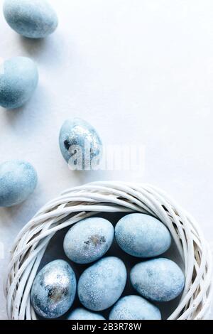 Blue ombre eggs on light background in the white nest. Spring flowers. Daylight. Stylish minimal Compositions in pastel colors. Easter concept. Flat lay, top view. Copy space. Stock Photo