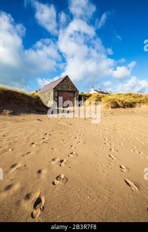 The Lifeboat house and rooftops of the white Pilot's cottages from the beach on Llanddwyn island, Anglesey Stock Photo