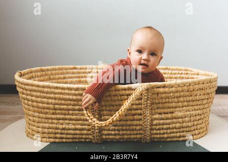 Adorable six month old baby girl in a basket on the floor and looking into the camera Stock Photo