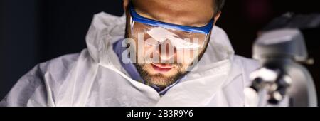 Man laboratory repairs instrument near microscope Stock Photo