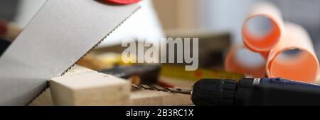 Hand saw mounted on wooden bar, near drill hammer Stock Photo