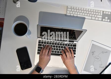 Overhead shot of womans hands working on apple laptop Stock Photo