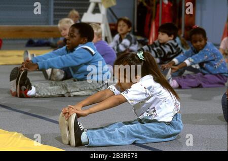 Austin Texas USA: Kindergarten students stretch to touch their toes during physical education class in elementary school gym. ©Bob Daemmrich Stock Photo