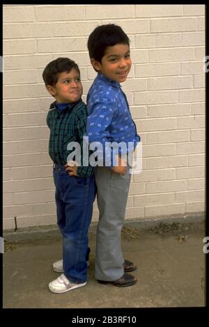 Austin Texas USA: Hispanic four-year-old boy measures his height against taller five-year-old boy. ©Bob Daemmrich Stock Photo