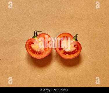 Red tomato cut in half isolated in a brown background viewed from above - flatlay look Stock Photo