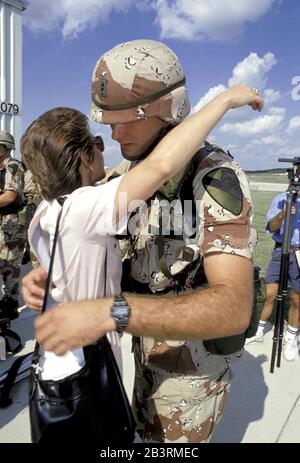 Fort Hood, Texas USA, 1990: Young  American army soldier wearing desert-colored camouflage uniform shares a goodbye hug with a loved on before leaving his post for a tour of duty in the Middle East in the lead-up to the 1991 Gulf War. ©Bob Daemmrich Stock Photo