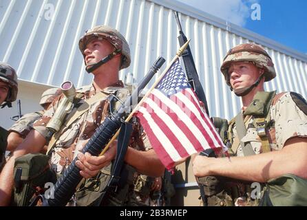 Fort Hood, Texas USA, 1990: Young  American army soldiers wearing desert-colored camouflage uniforms and carrying weapons leave their post for a tour of duty in the Middle East in the lead-up to the 1991 Gulf War. ©Bob Daemmrich Stock Photo