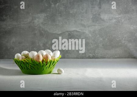 Still life with Easter eggs on a wooden table covered with a tablecloth with space for an advertising product. Cozy home interior. Stock Photo