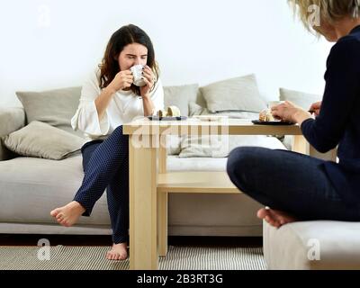 Two women sit eating and talking Stock Photo