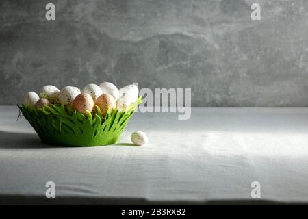 Still life with Easter eggs on a wooden table covered with a tablecloth with space for an advertising product. Cozy home interior. Stock Photo