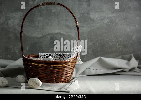 Still life with Easter eggs on a wooden table covered with a tablecloth with space for an advertising product. Cozy home interior. Stock Photo