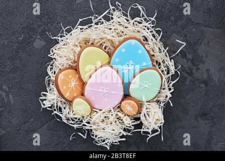 Easter card with gingerbread cookies. Easter spring decorative composition with nest and gingerbread cookies in form of eggs on gray background. Stock Photo