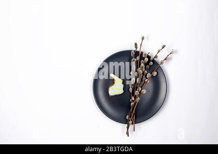 Black plates with gingerbread cookies, willow branches and Easter decoration on a gray concrete background.  Spring holiday concept. Copy space, Easte Stock Photo